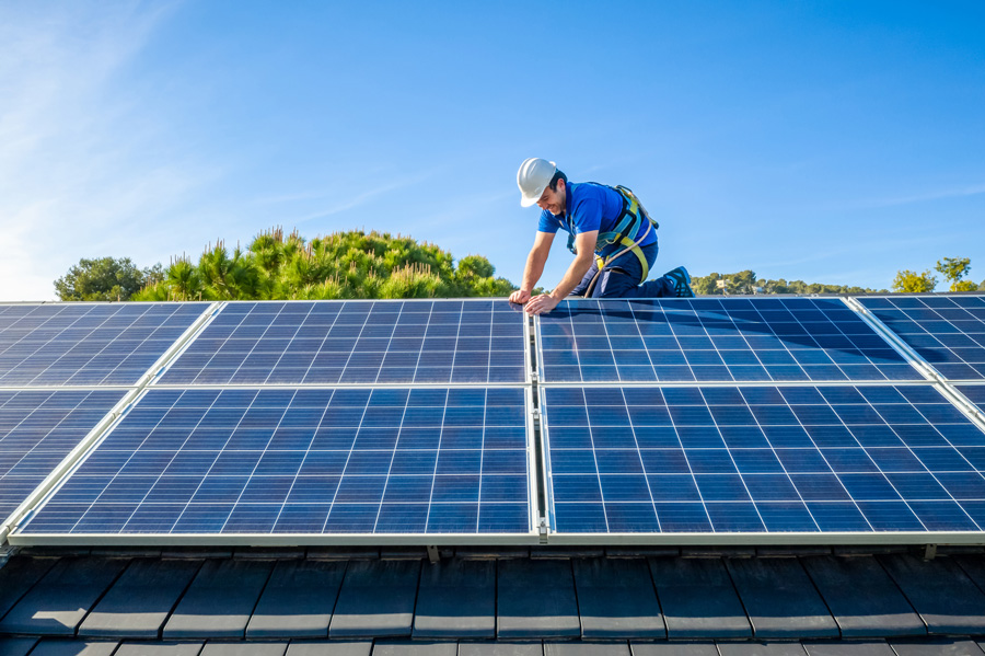 Worker installs solar panels on rooftop