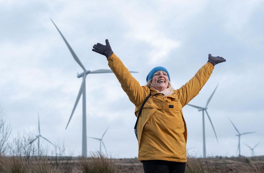 Michele Lennox celebrates in front of a windfarm