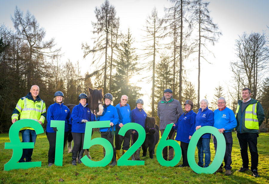 Members of Shiresmill Therapy Riding Centre holding up oversized numbers displaying, '£15260' donated to the charity.