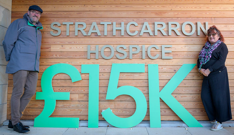 Strathcarron Hospice members stand next to oversized numbers indicating £15k donated to the charity.