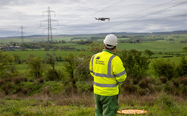 SP Energy Networks Employee flies a drone over electricity lines in the countryside.